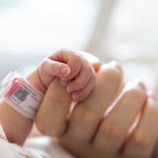 Baby's hand clutching midwife's hand