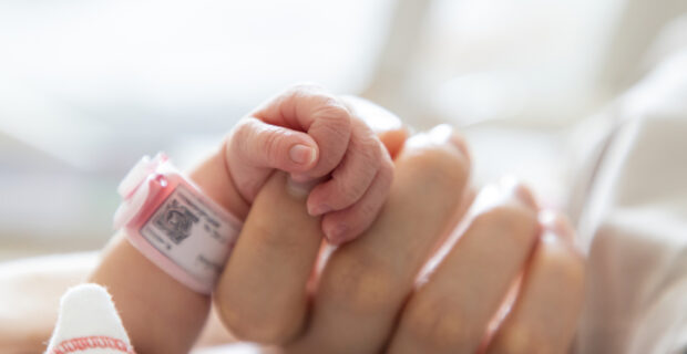 Baby's hand clutching midwife's hand